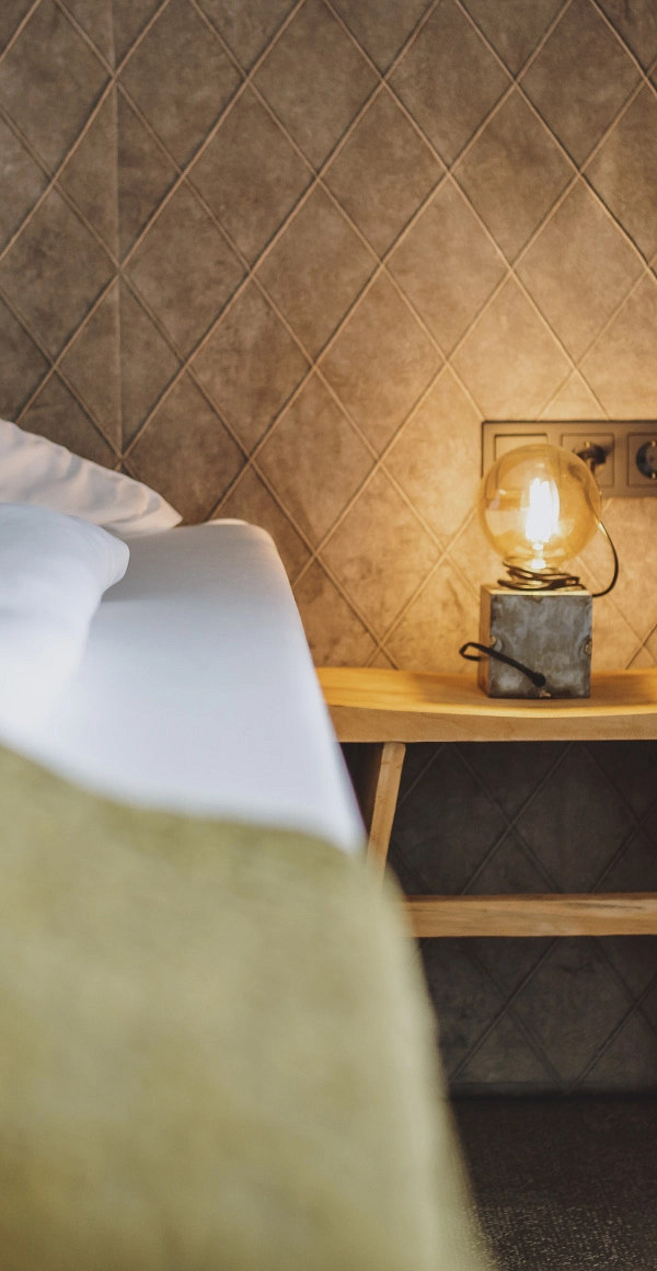 Detailansicht eines Zimmers mit Bett und dekorativer Lampe