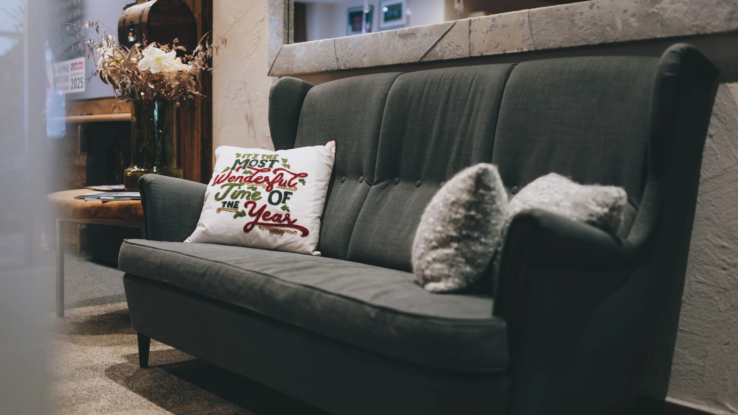 Grau Sofa mit Kissen 'Most wonderful time of the year' und Dekoration im Hintergrund