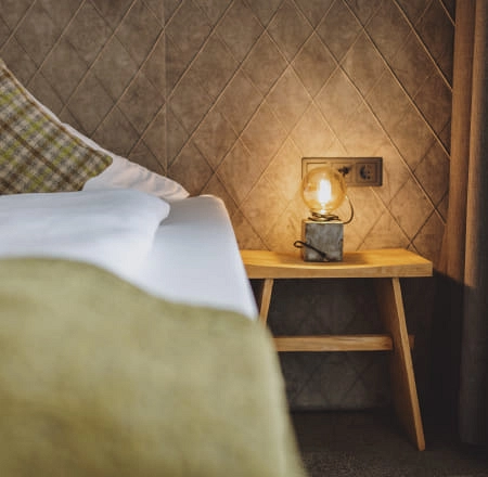 Detailaufnahme eines Zimmers mit Bett, Kissen und Lampe auf einem Tisch