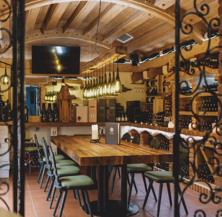 Weinlounge mit Holztisch, Stühlen und Weinregalen im Hintergrund