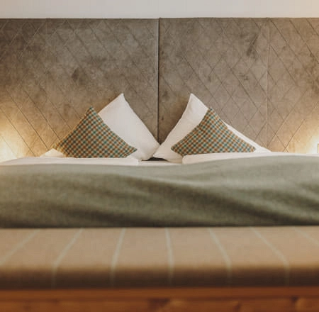 Bett mit Kissen und grauem Überwurf in einem modernen Raum.