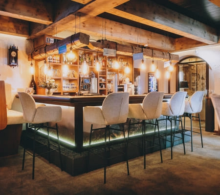Moderne Bar mit Holzdecke und eleganten Barhockern