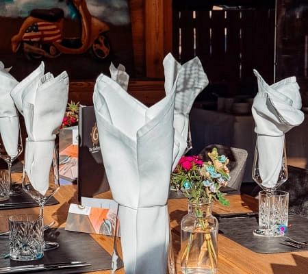 Gedeckter Tisch mit weißen Servietten und Blumenarrangement