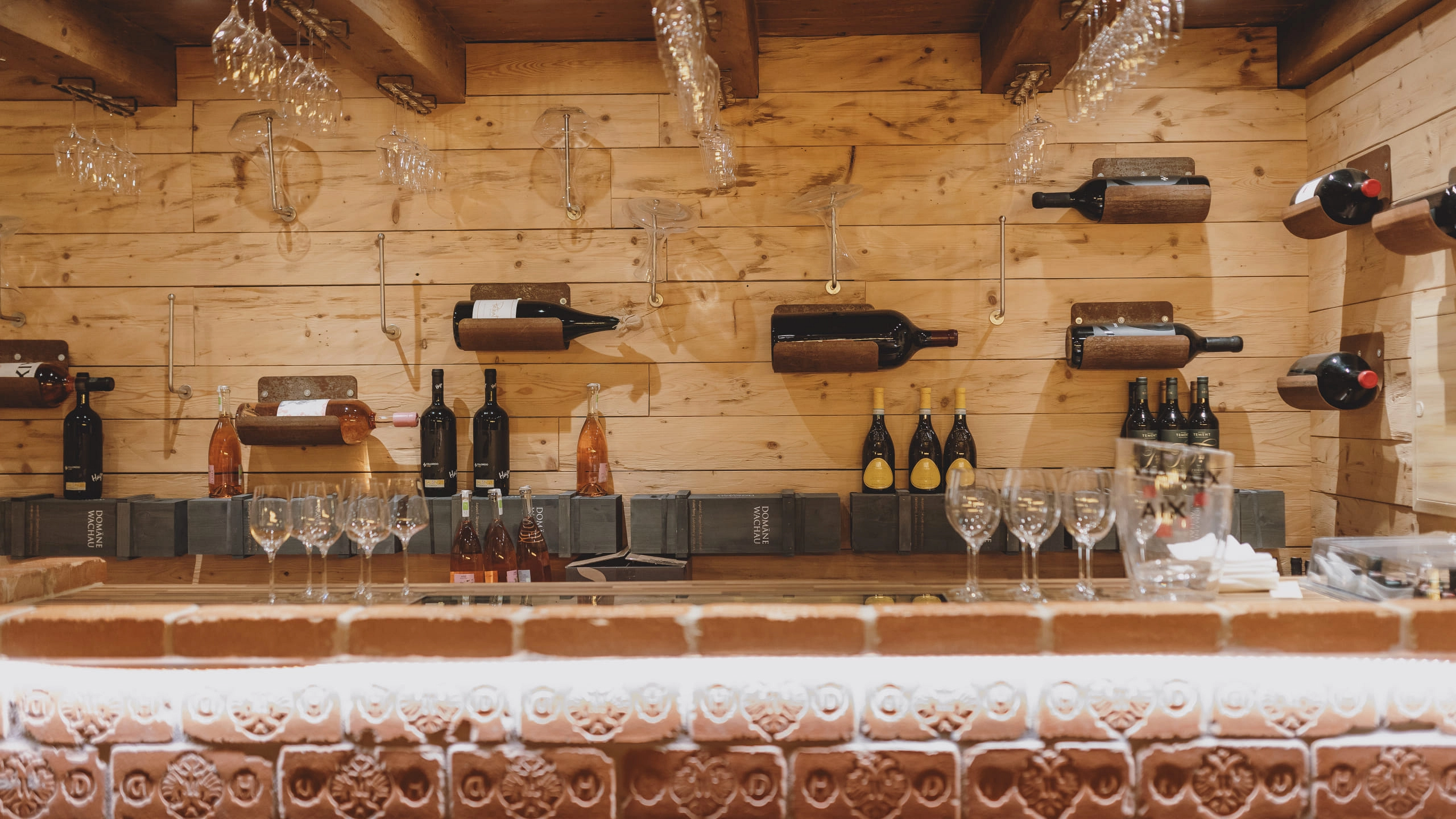 Holzwand mit Weinflaschen und Gläsern in einer Weinlounge