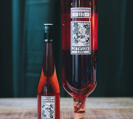 Zwei Flaschen rosé Wein mit dekorativen Etiketten auf einem Holztisch