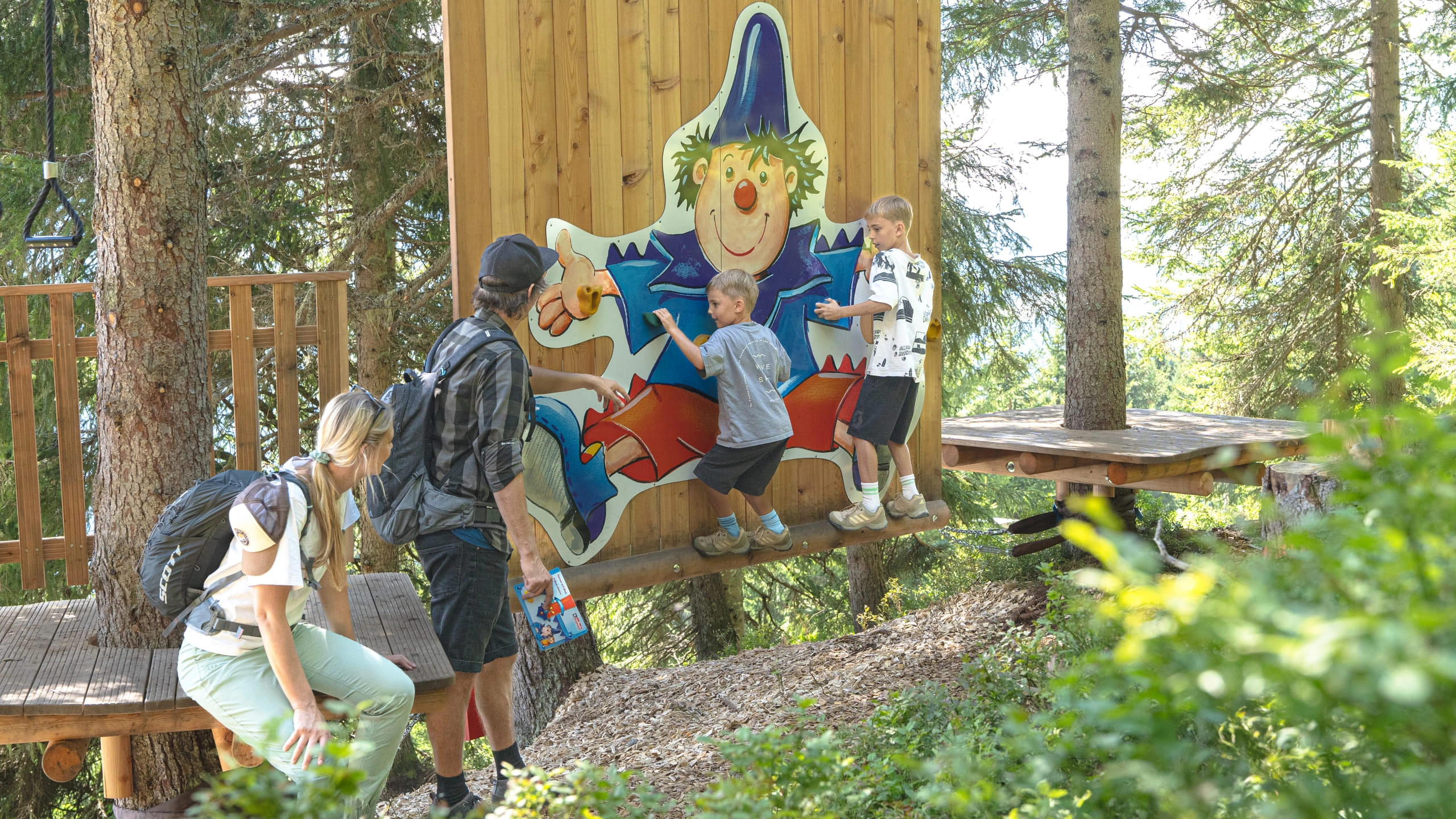 Kinder und Erwachsene erkunden den Montelinos Erlebnisweg mit einer Spielfigur.