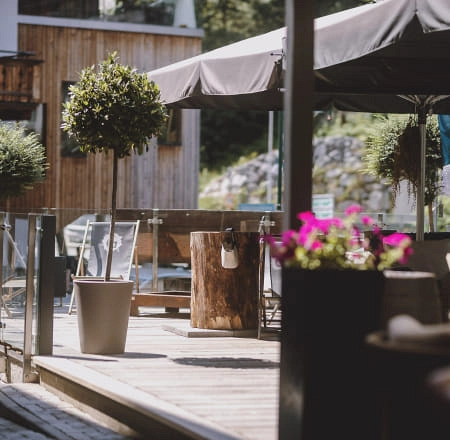 Terrasse mit Pflanzen, Holzmöbeln und Sonnenschirmen