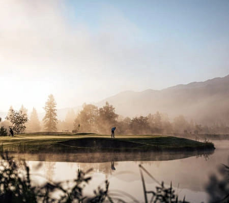 Golfspieler am frühen Morgen mit Nebel über dem See in Zell am See