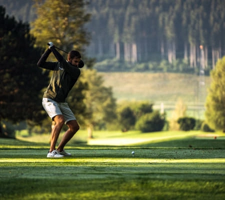 Golfspieler auf einer schönen Golfbahn mit Bäumen und Bergen im Hintergrund