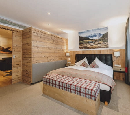 Gemütliches Hotelzimmer mit Holzakzenten, Doppelbett und Bergkunstwerk