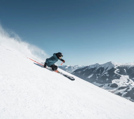 Skifahrer auf einer Piste in Saalbach Hinterglemm bei klarem Himmel