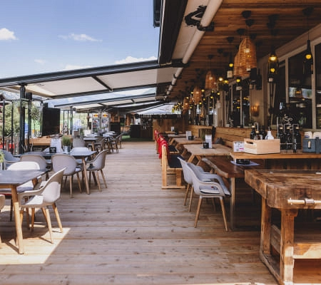 Terrasse mit Tischen und Stühlen bei schönem Wetter