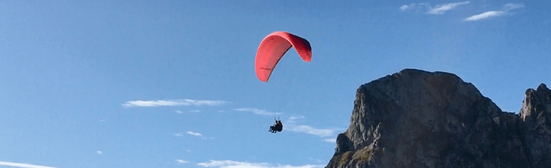 Paragliding über einem Berg mit blauem Himmel
