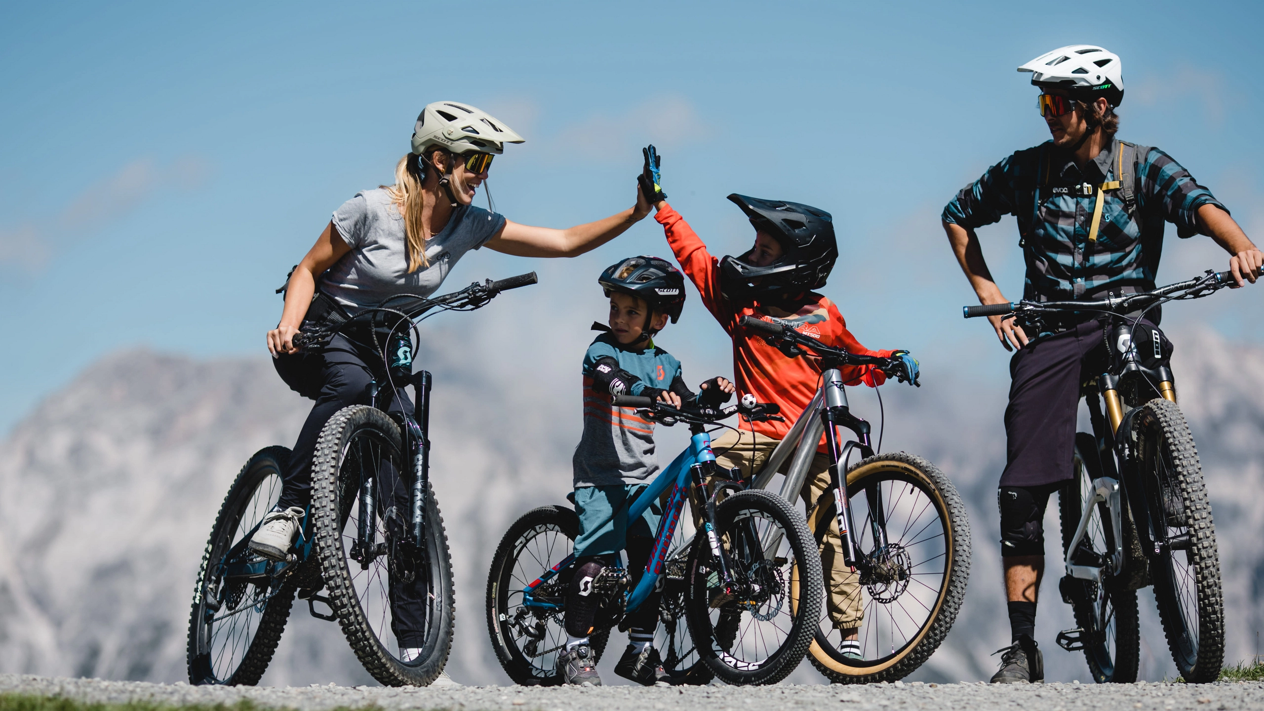Familie beim Radfahren in den Bergen, Kinder heben die Hände.